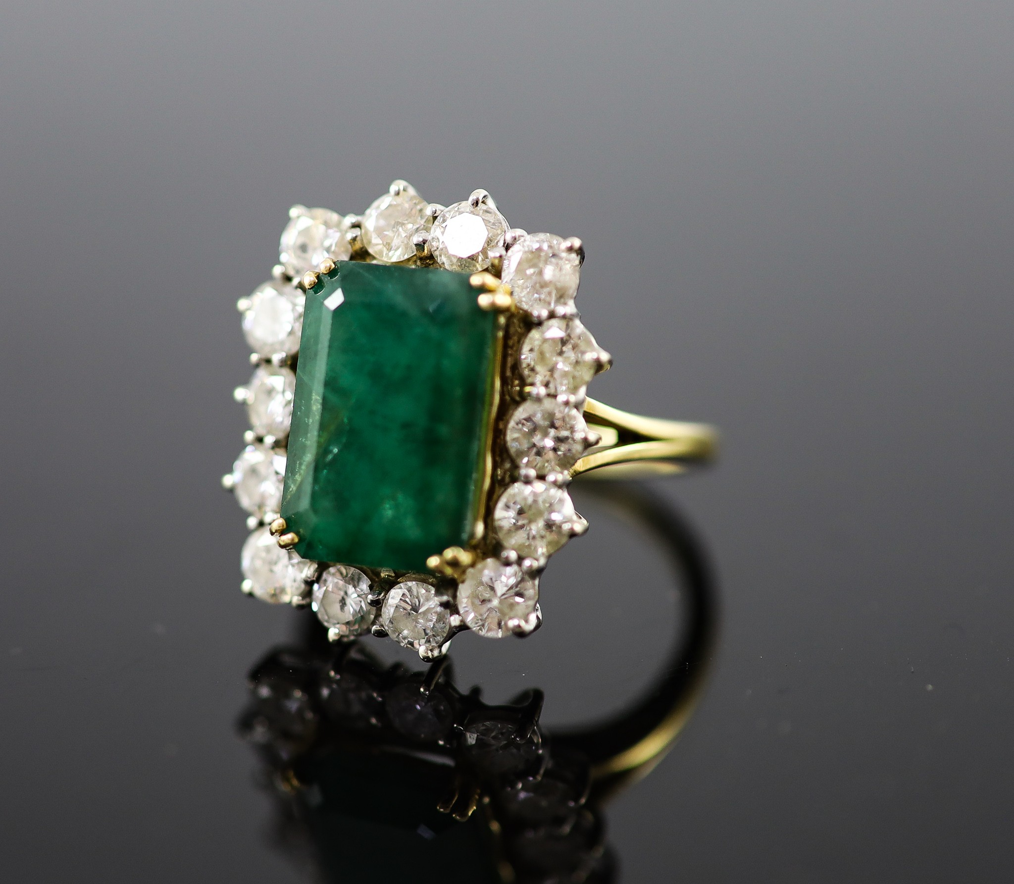 A mid to late 20th century 18ct gold, emerald and diamond set shaped rectangular cluster ring